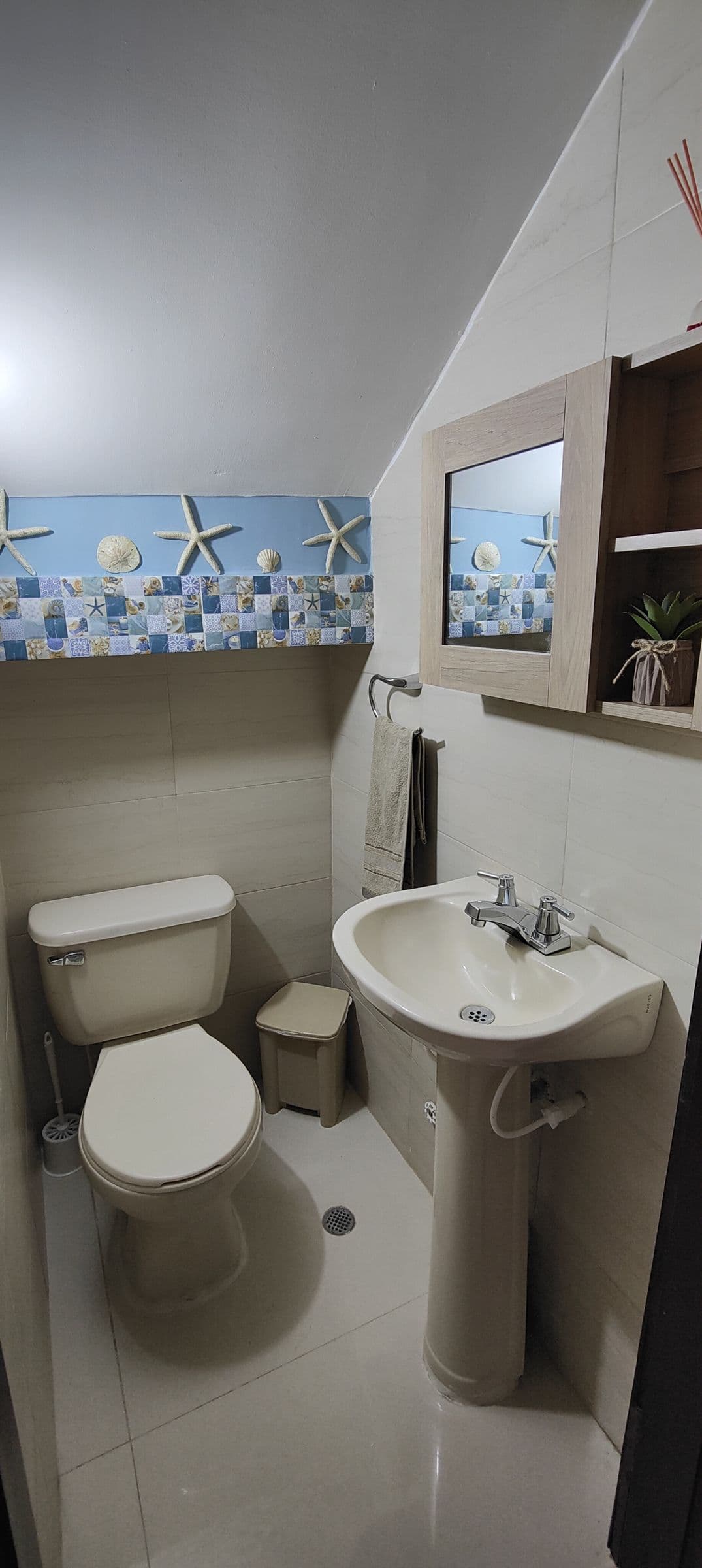 Un bagno piccolo con lavabo a colonna e una fascia di piastrelle con le conchiglie