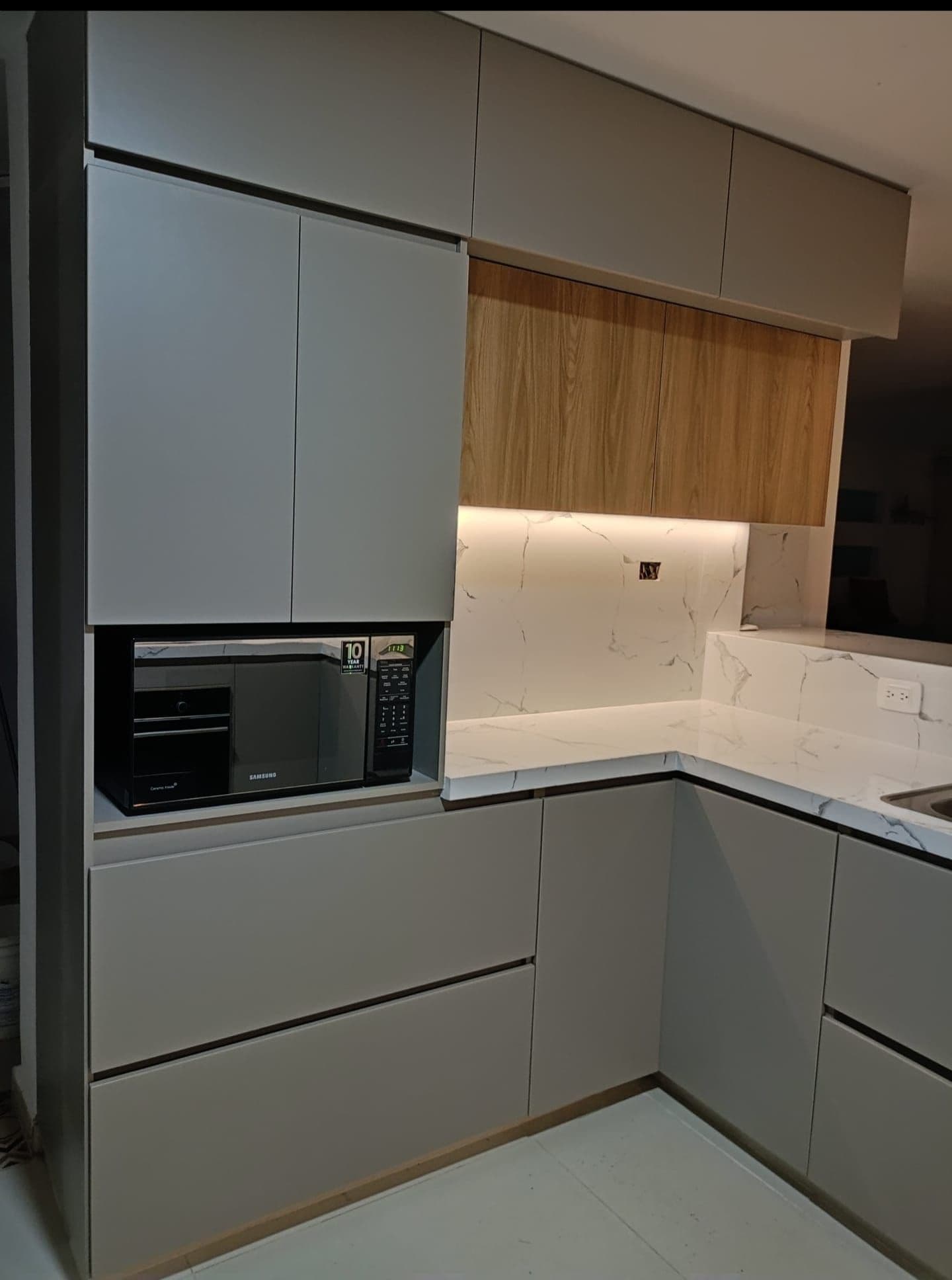 I pensili grigi e in legno della cucina, con il microonde a incasso