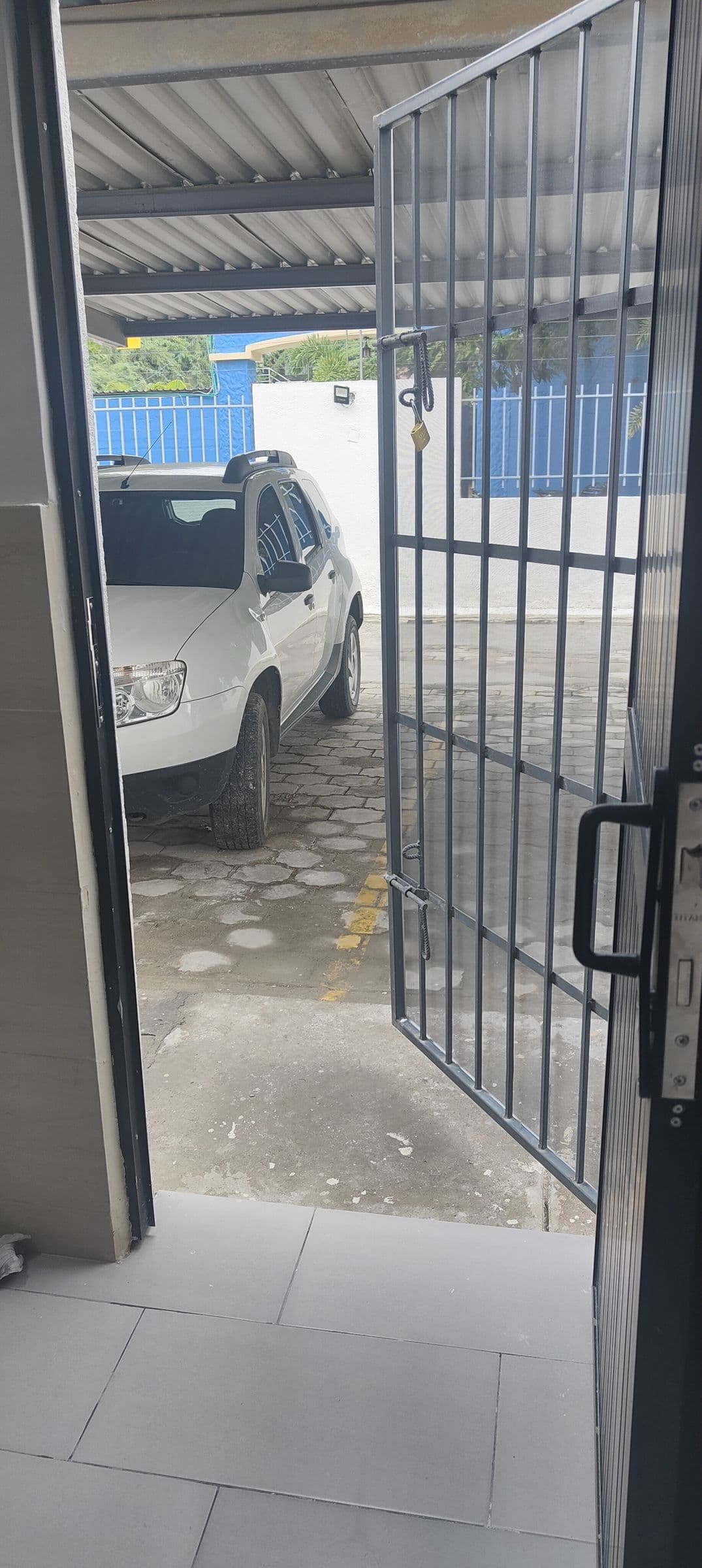 La porta di servizio aperta sul posto auto coperto, con un’auto parcheggiata