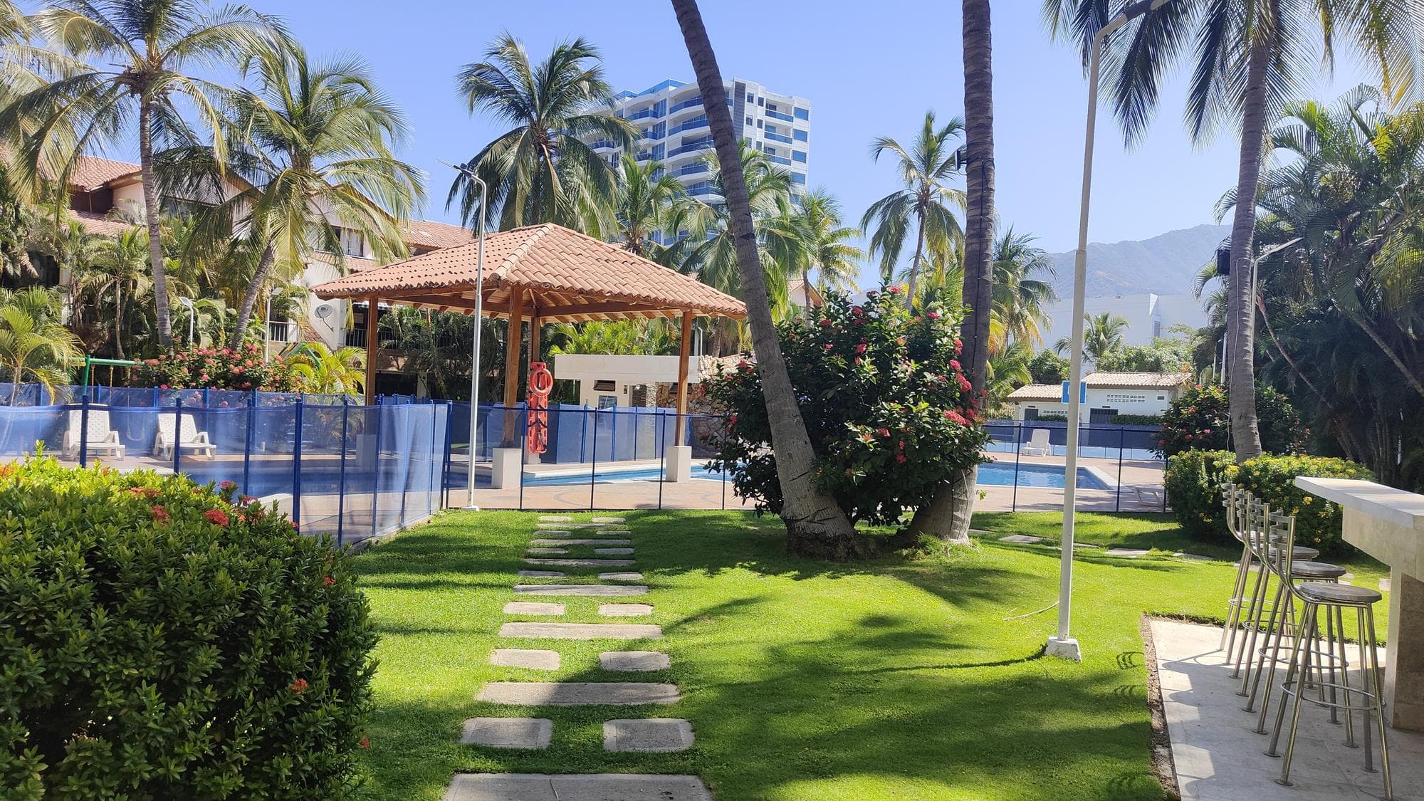 Il prato con il vialetto di pietre verso la piscina, fra le palme