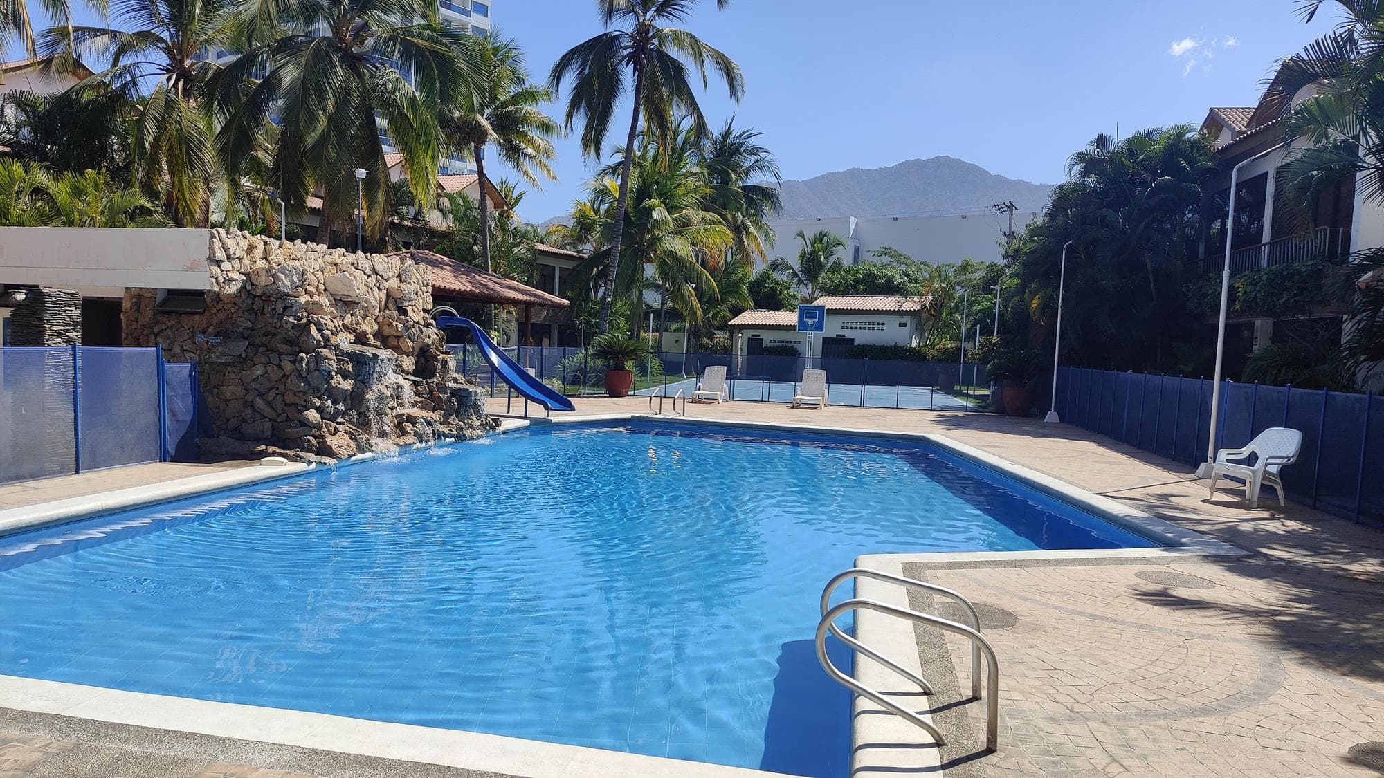 La piscina della residenza Princesa del Mar Villas, con lo scivolo, le palme e la Sierra sullo sfondo